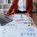woman meticulously plans a finance audit, using a computer and calculator to review budget documents